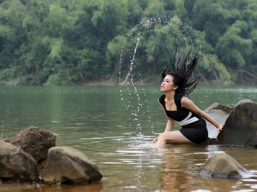 Featured Image Of A Young Lady In A Lake With An Arc Of Water Splashed From Her Hair.