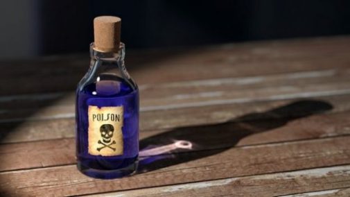 Image Of A Small Corked Jar/Bottle Labelled Poison On A Wood Surface.