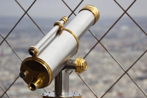 Featured Topic Image Telescope Pointing Upperly Through Mesh Fence. Out Of Focus City Background.