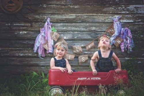 photocredit/thanks:lisa runnels:pixabay Featured Image Gemini Twin Children Sitting In A Toy Truck Playing Outside. A Colorful Banner Flies On The Wall.