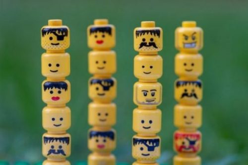 20+ Lego Figurine Heads Arranged Totem Style In A Row Of Four Stacks.