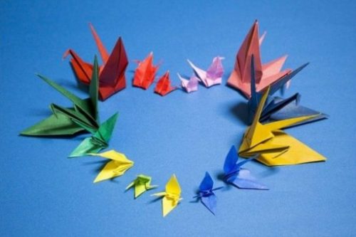 Set Of Colored Origami Figures Arranged In A Heart Shape On Blue Background.