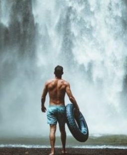 Man With Rubber Tyre Approaches Large Waterfalls.