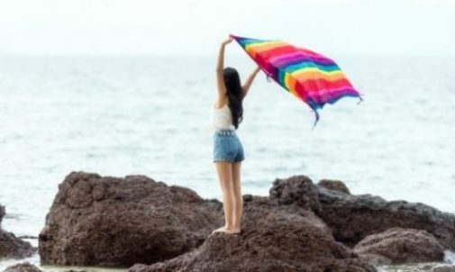 photocredit/thanks:qinggan.jiayuan Image Of A Young Woman Holding Up A Bright Towel Near The Beach Shoreline.