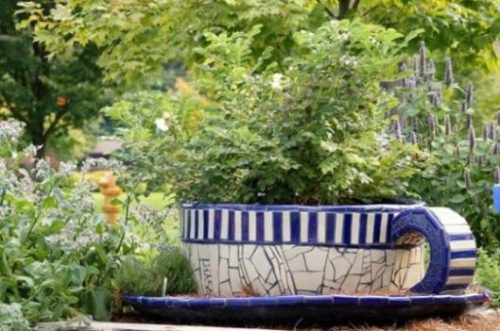 Image Of A Giant Size Blue And White Teacup Amidst A Herb Garden.