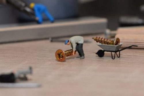 Image Of Tiny Toy Workers Barrowing Screws.
