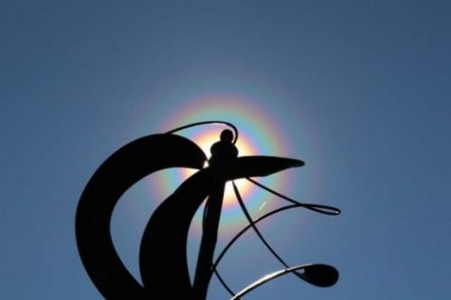 Image Of A Rainbow Halo Around The Ends Of A Metal Sculpture.