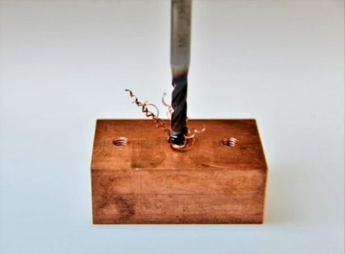 Image Of A Small Block Of Copper Being Drilled.